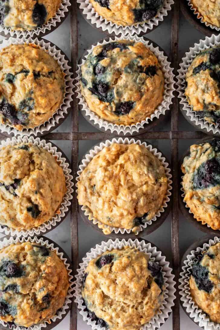 A vintage metal muffin tin filled with banana blueberry oatmeal muffins.