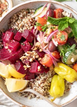 A Mediterranean Bowl filled with quinoa, Greek cucumber salad, marinated beets and toasted nuts.