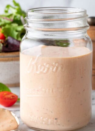 A clear glass mason jar filled with Thousand Island Dressing.