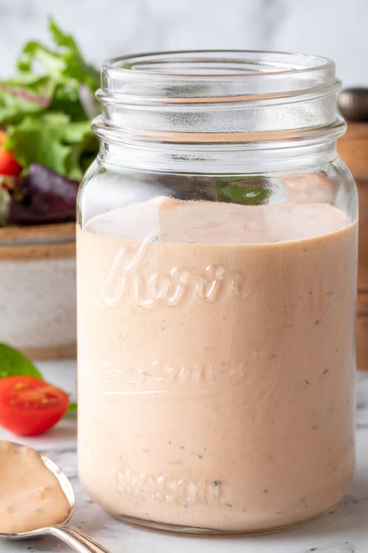 A clear glass mason jar filled with 1000 Island Dressing.