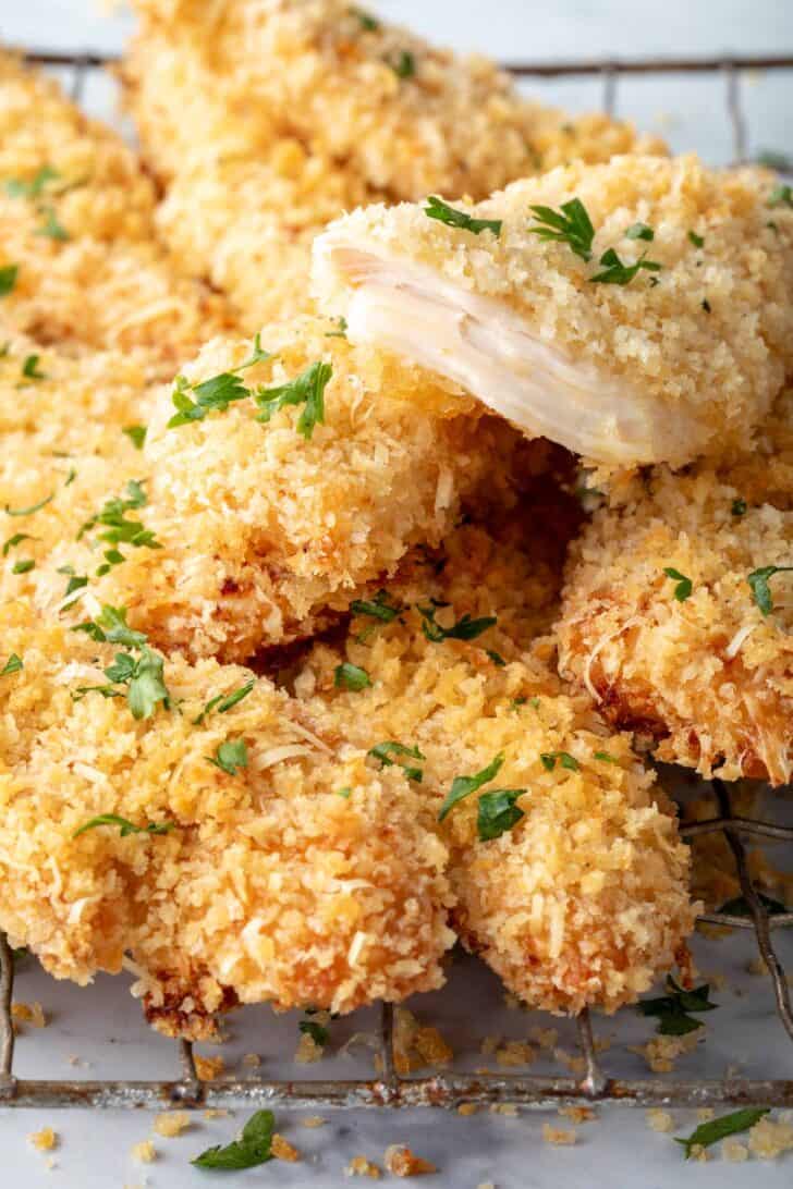 Oven baked chicken tenders piled on a wire cooling rack.