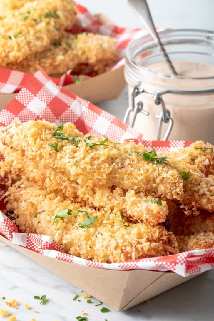 Two deli paper containers filled with crispy pieces of poultry.