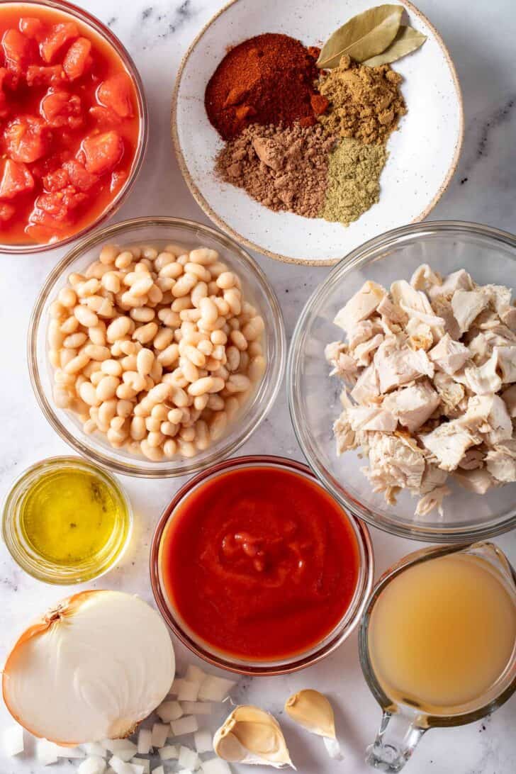 Small bowls filled with broth, tomato sauce, chopped tomatoes and a mix of seasonings.