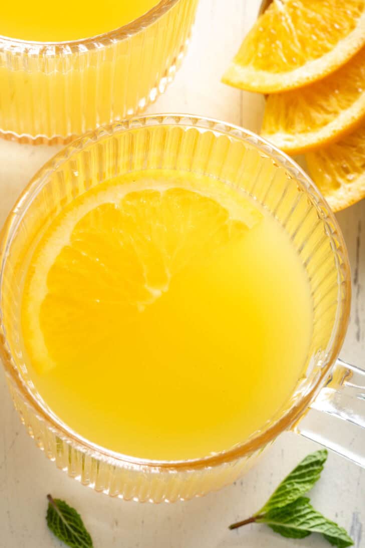 A clear glass mug filled with apple cider vinegar and green tea.