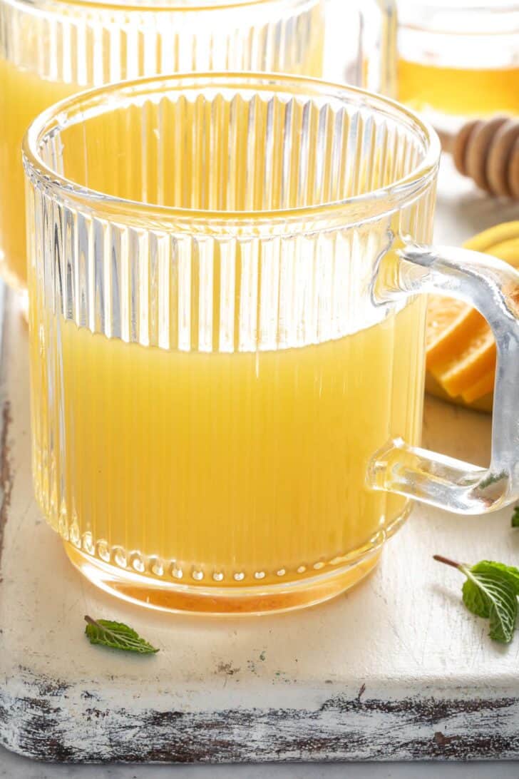 A clear glass mug filled with a citrus drink.