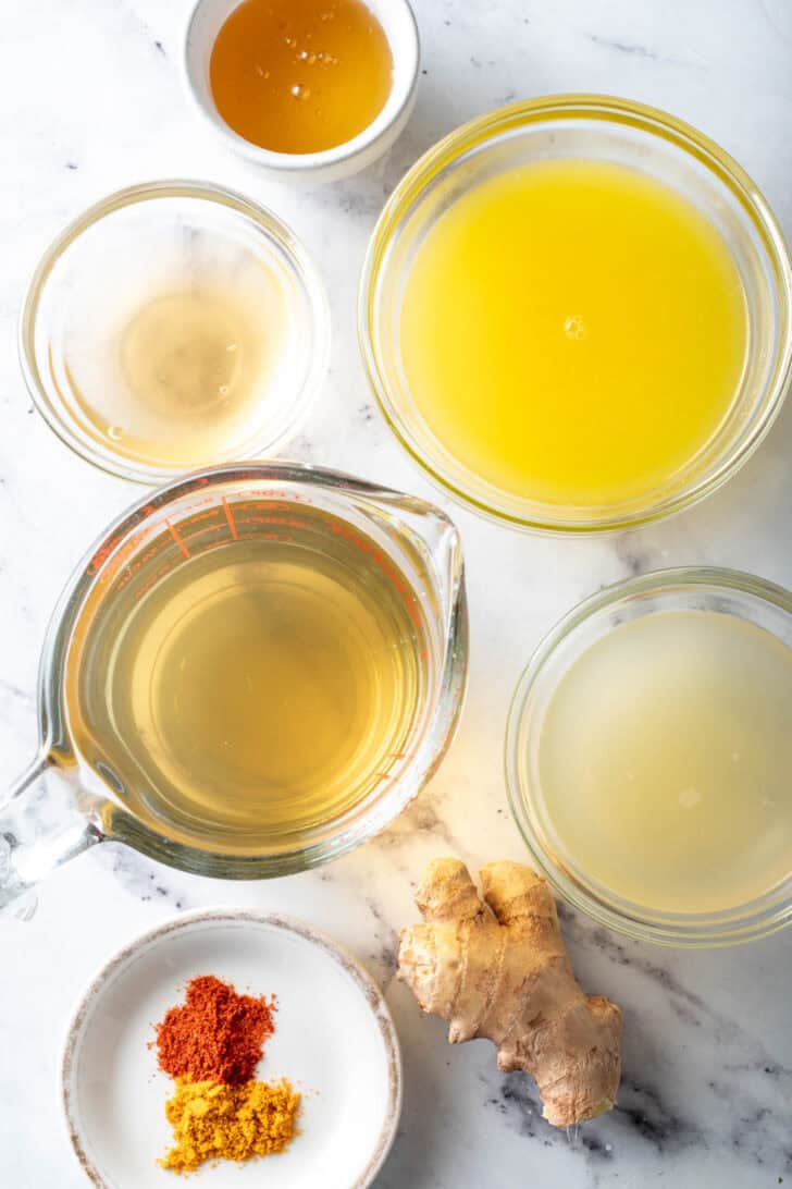 Small clear bowls filled with orange juice, lemon juice, and honey.