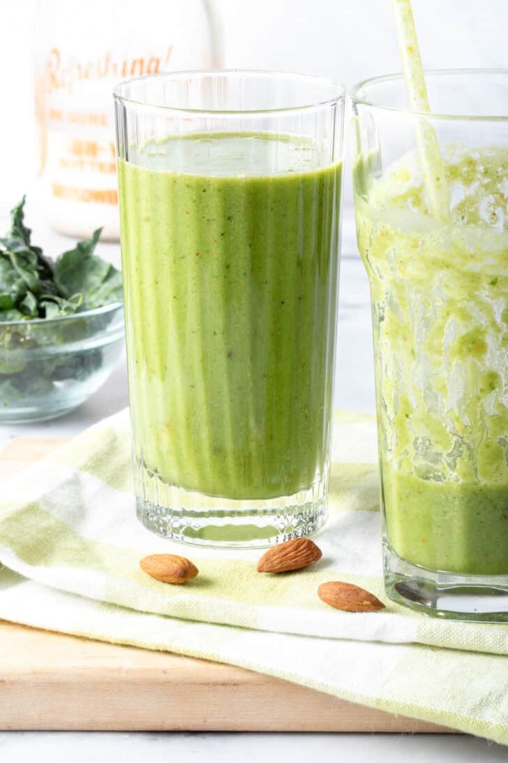 Two drinking glasses filled with kale smoothie.