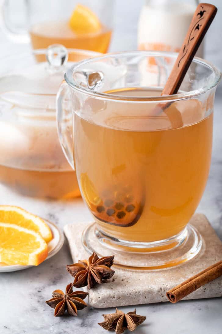 A clear glass mug filled with chai green tea.