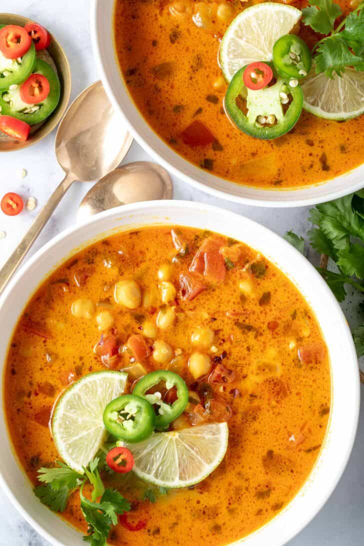 Two white bowls filled with chickpea coconut curry soup