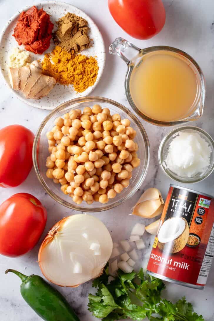 Clear glass bowls filled with legumes, chicken broth, coconut oil and spices.