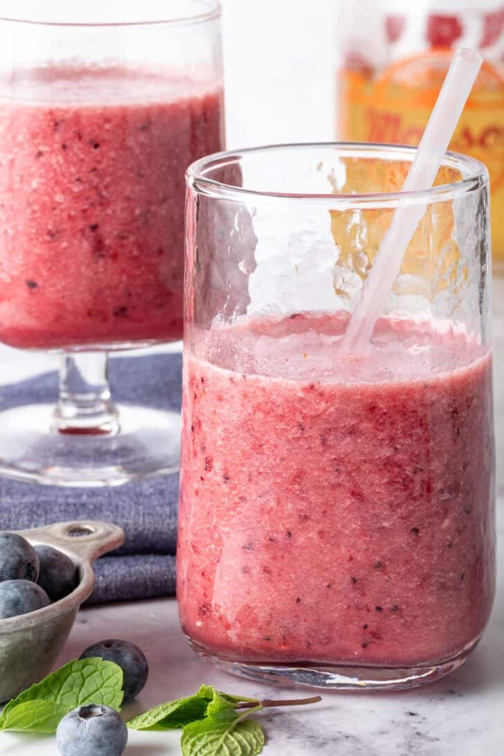 Two clear glasses filled with mixed berry green tea smoothie.