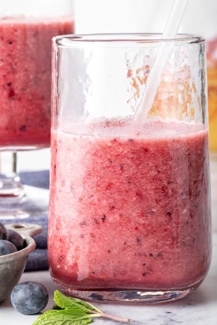 Two clear glasses filled with green tea berry smoothie.