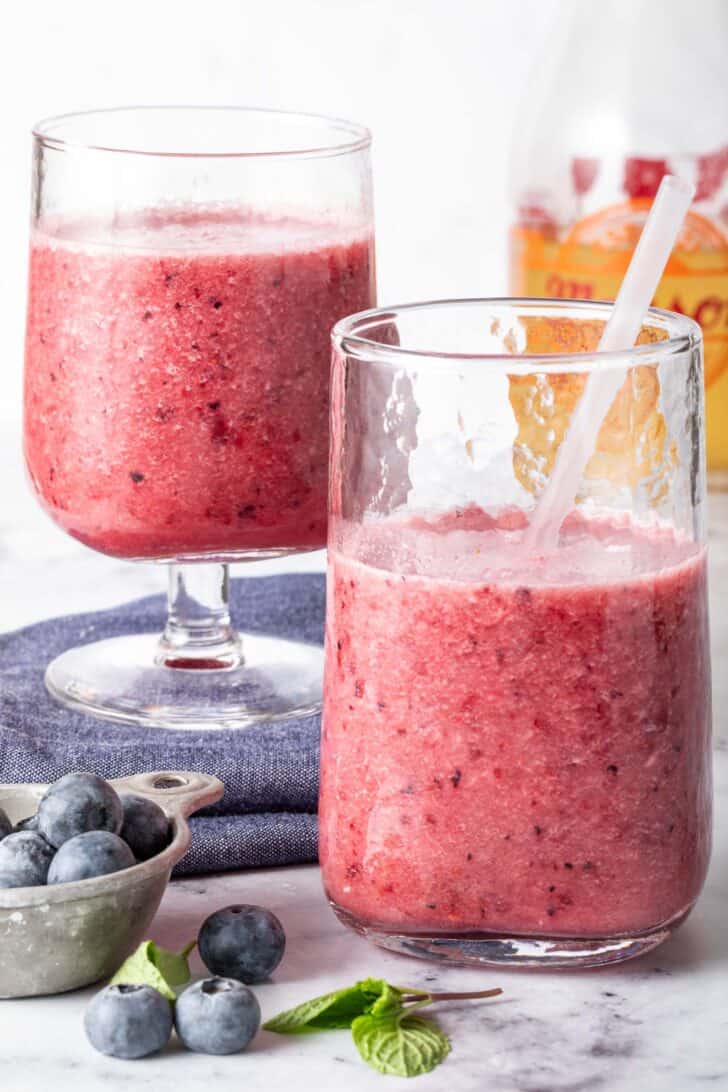 Two clear glasses filled with green tea fruit smoothie.