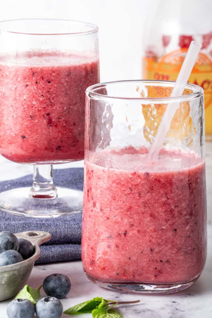 Two clear glasses filled with a mixed fruit drink.