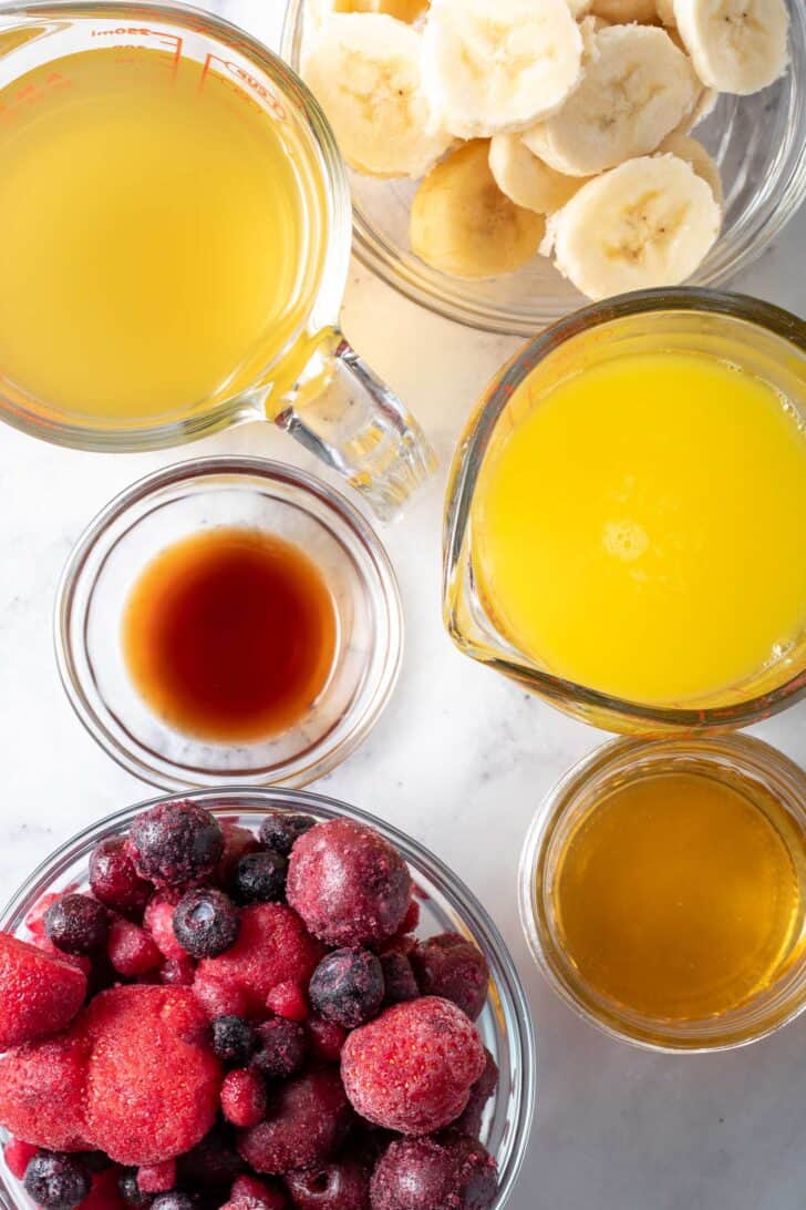 Clear glass bowls filled with fruit, orange juice, sliced bananas and vanilla extract.