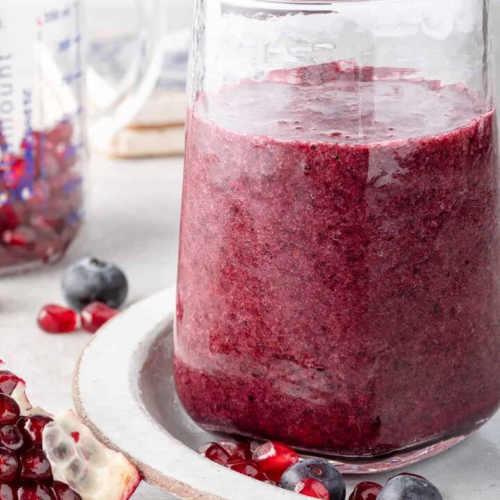 A clear drinking glass filled with Pomegranate Smoothie.