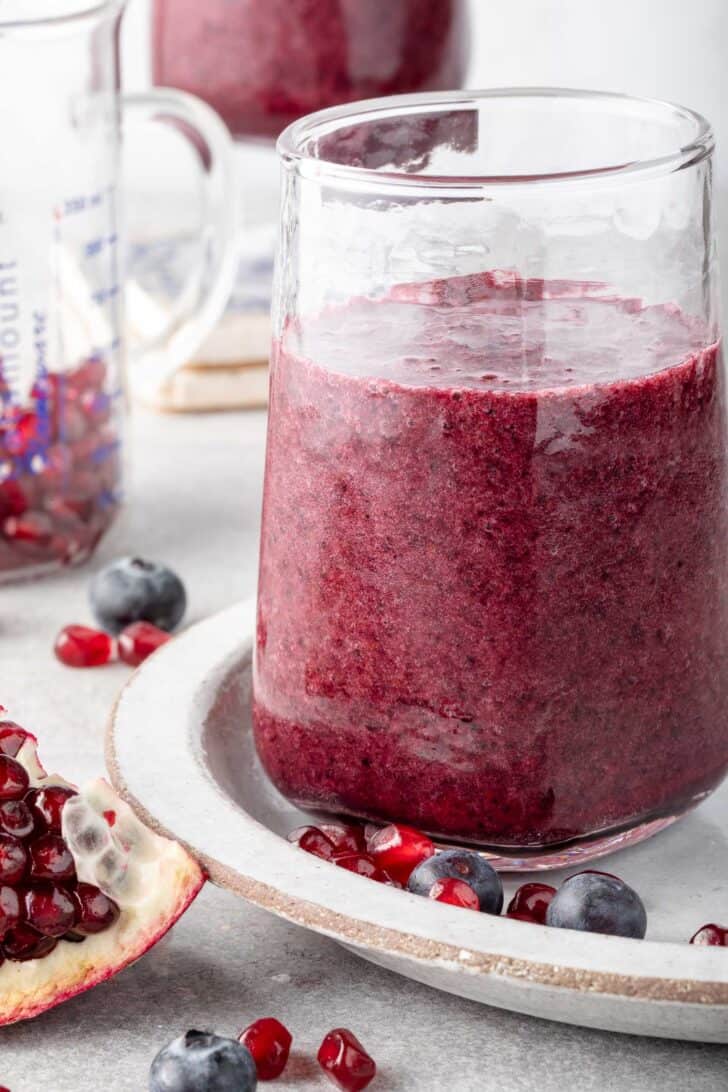 Two clear glasses filled with pomegranate smoothie.