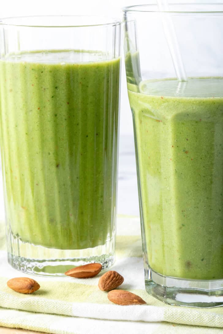 Two drinking glasses filled with a creamy green drink.