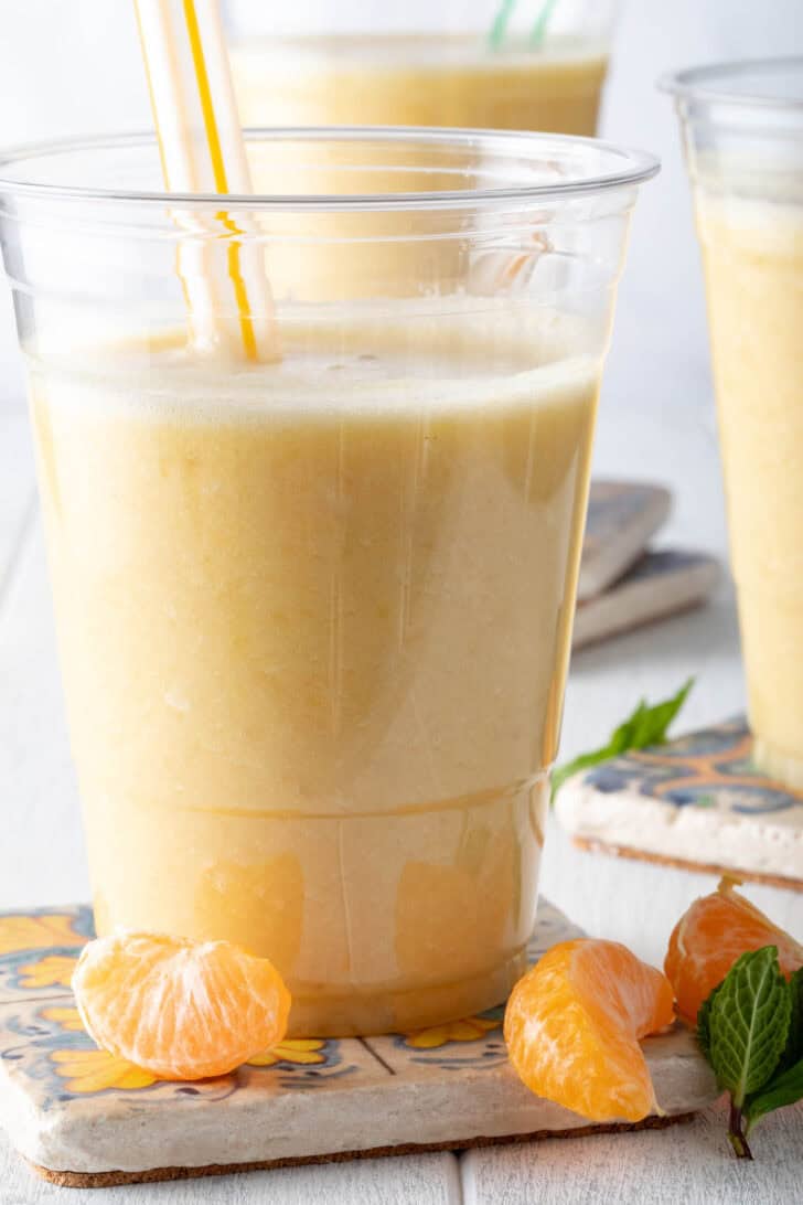 A clear glass filled with pineapple smoothie.