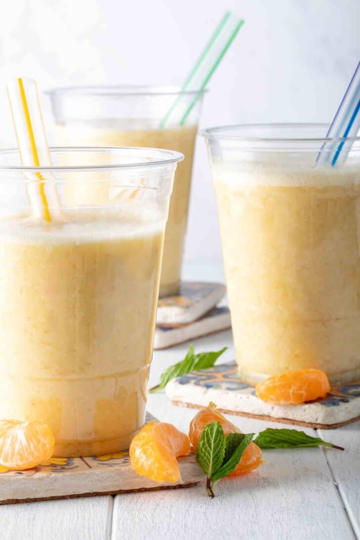 Three clear glasses filled with pineapple banana smoothie.