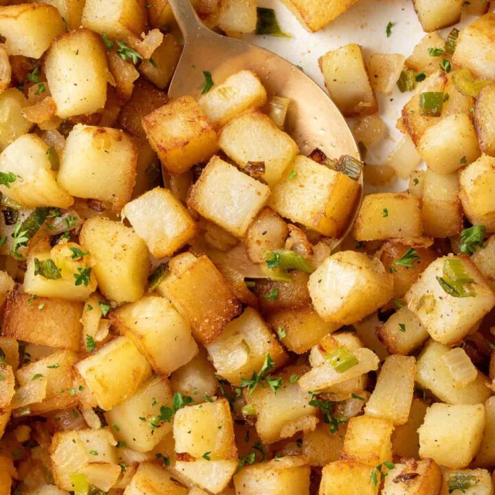 A white skillet filled with crispy breakfast potatoes.