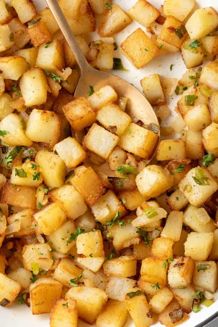 A white skillet filled with crispy Breakfast Potatoes.