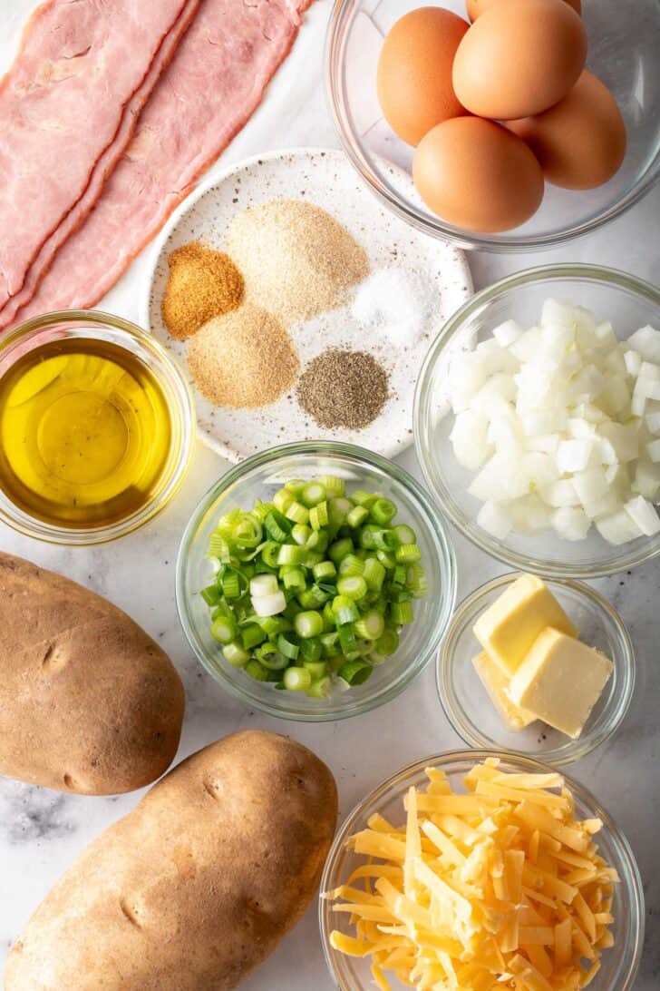 Small glass bowls filled with eggs, grated cheese, chopped onions, butter and spices.