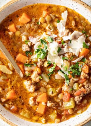 A cream colored bowl filled with Sausage Lentil Soup.