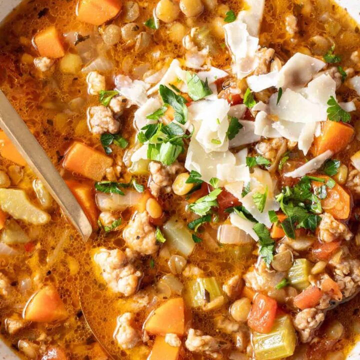 A cream colored bowl filled with Sausage Lentil Soup.