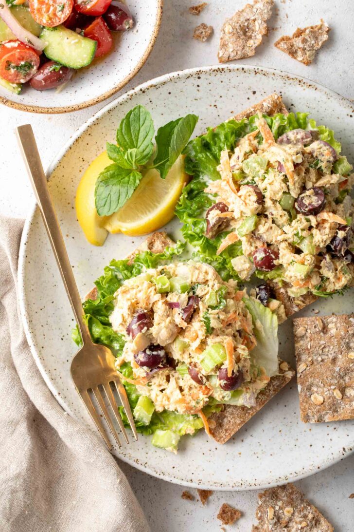 A white plate with two scoops of canned salmon salad on lettuce leaves.