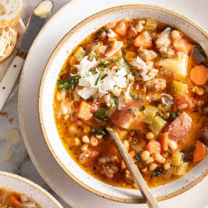 A white bowl filled with Sausage Kale White Bean Soup.