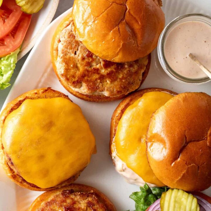 A platter with ground turkey patties and buns on it.